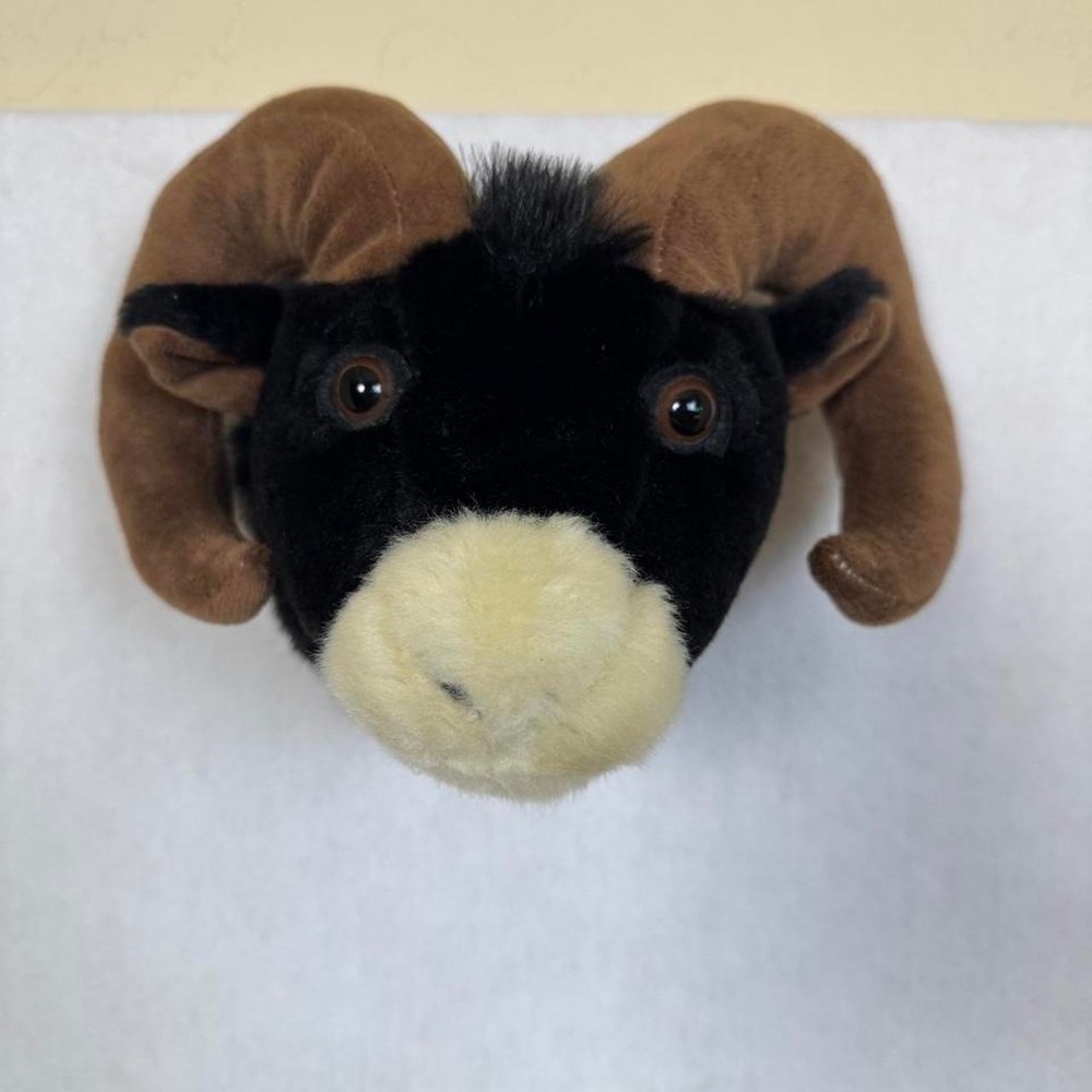 Black ram head plush wall mount with brown horns and cream-colored muzzle